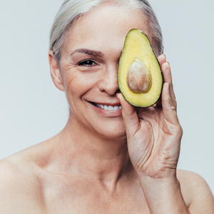 Mature woman with avocado covering her eye next to text about using pure, natural, and organic ingredients
